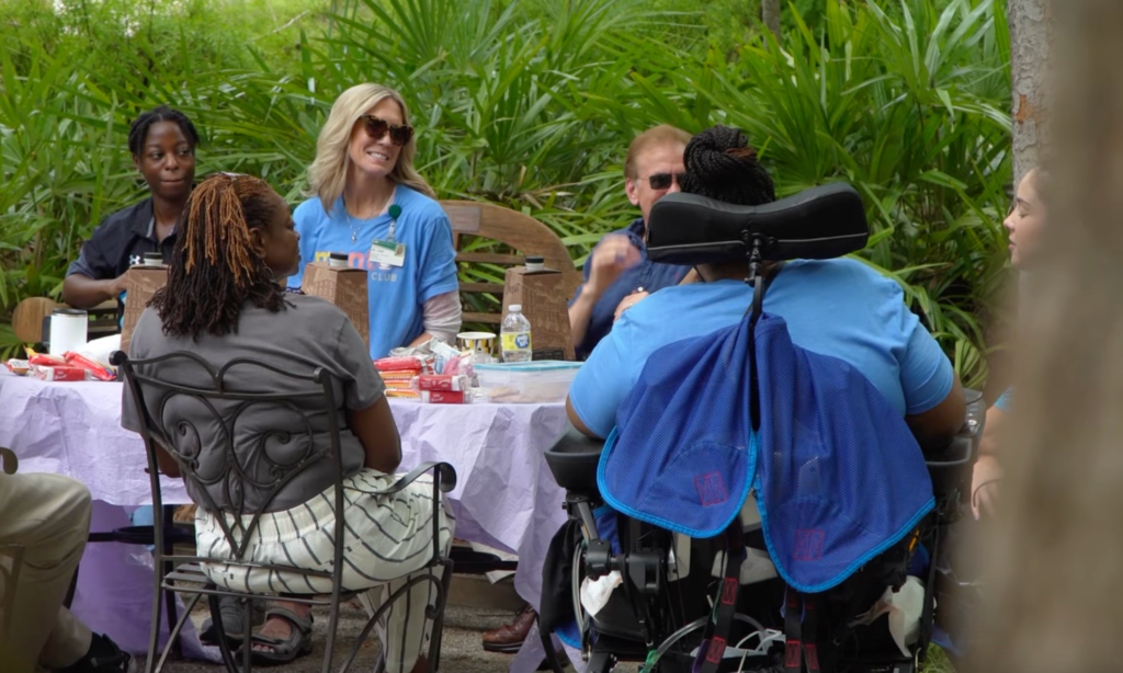 group of disabled and non disabled people together at a table outdoors